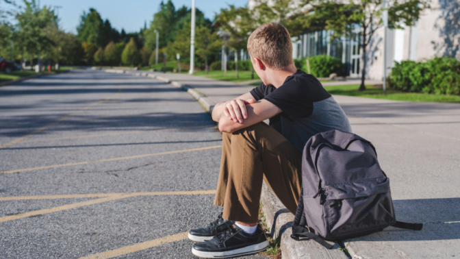 student sitting on kerb